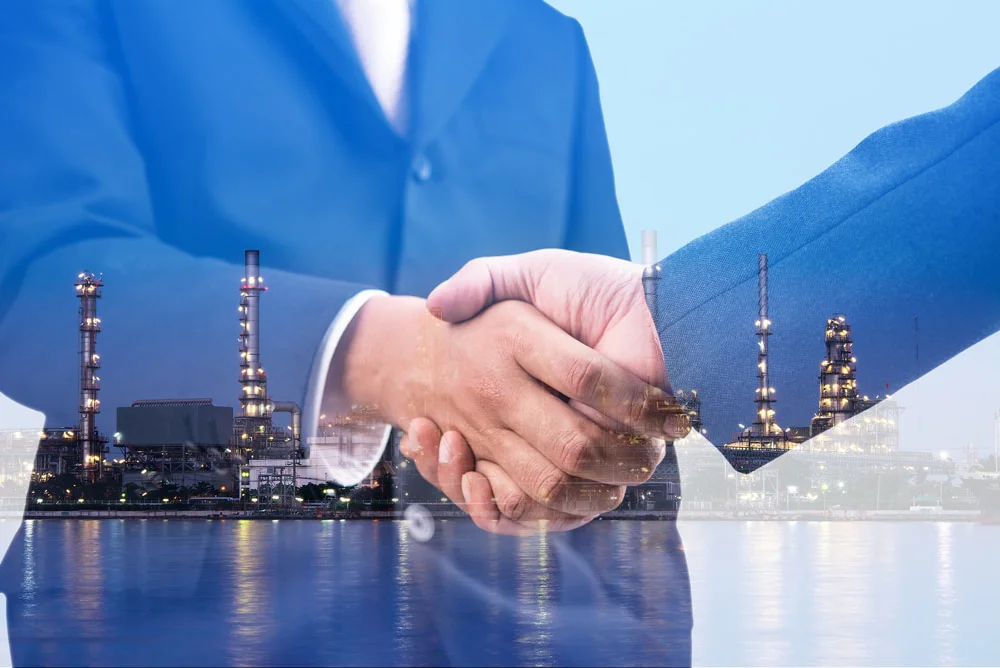 Händedruck und Raffinerieanlage bei Nacht